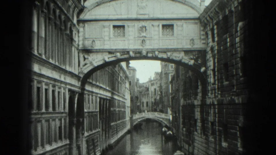 1975 Venice view of the Bridge of Sighs crossing a narrow canal, with stone facades and another small bridge in the distance.