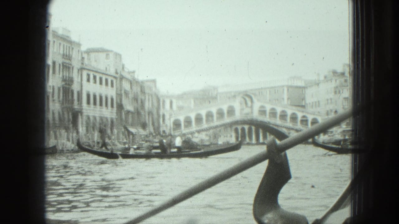 Gondola and Rialto Bridge seen across a Venice canal from inside a boat.