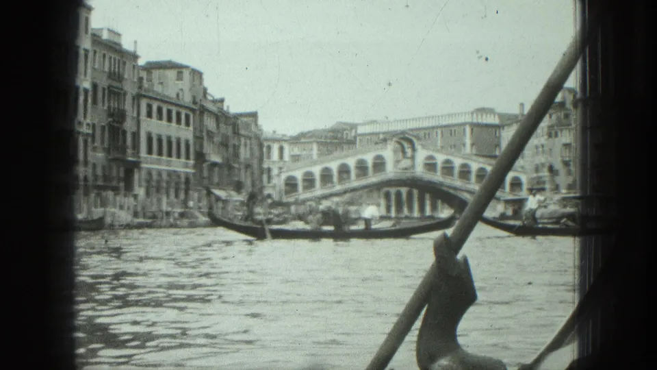 1975 Venice 8mm frame of the Rialto Bridge, canal water, gondolas, and waterfront buildings from a moving boat.