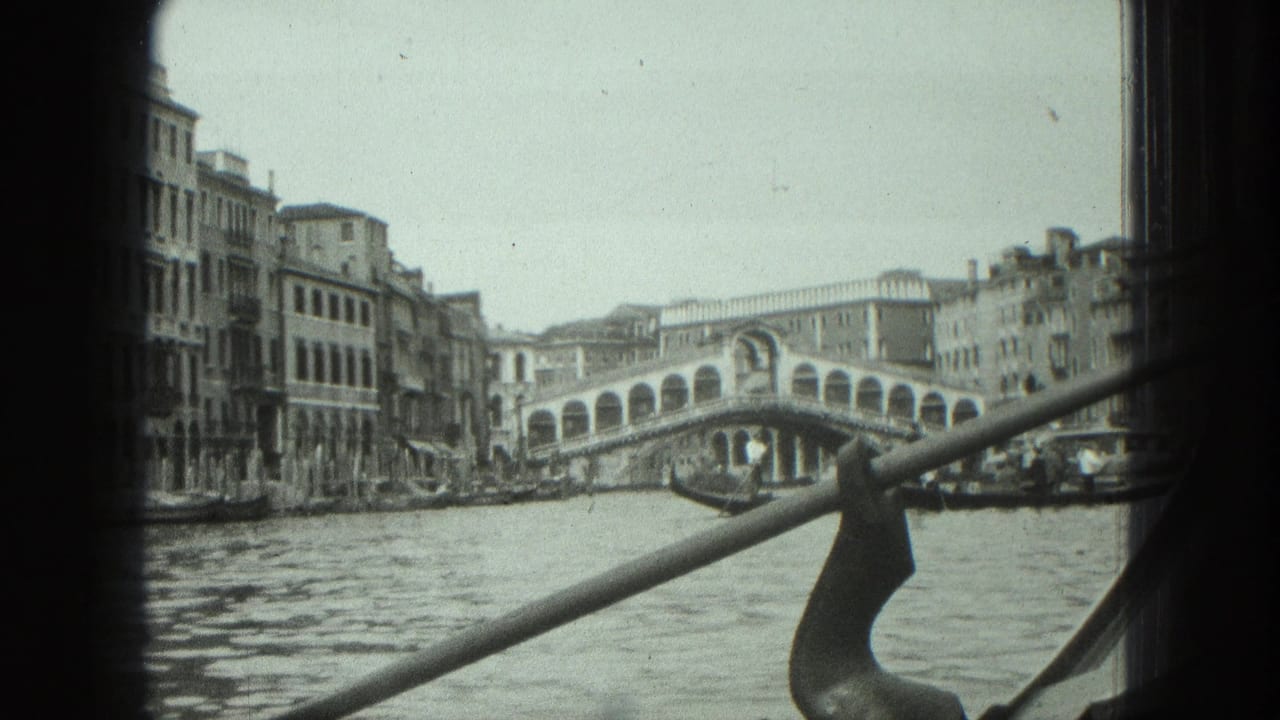 1975 8mm Venice view toward the Rialto Bridge from a moving boat, with canal water and gondola hardware crossing the frame.