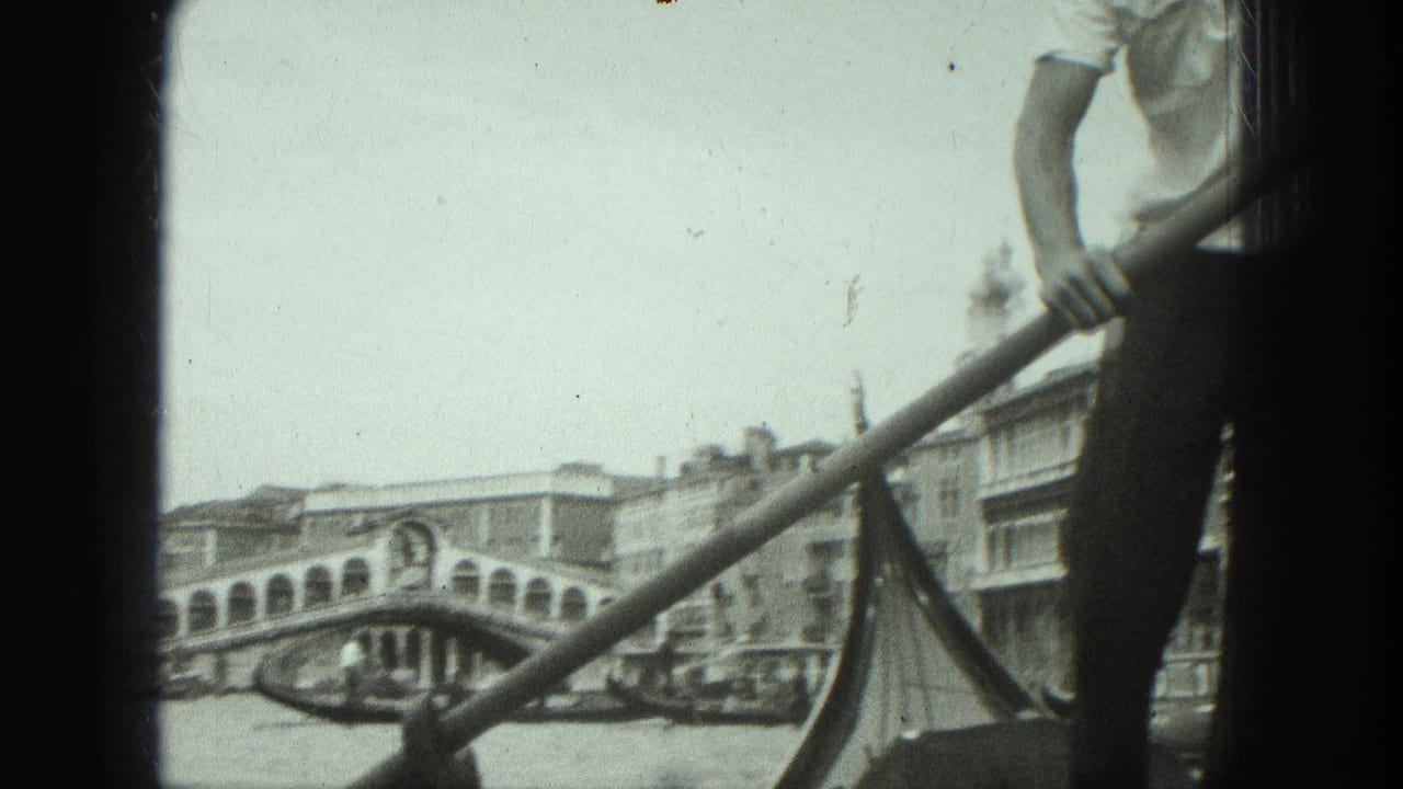Gondolier partly visible beside an oar, with the Rialto Bridge and canal buildings behind him.