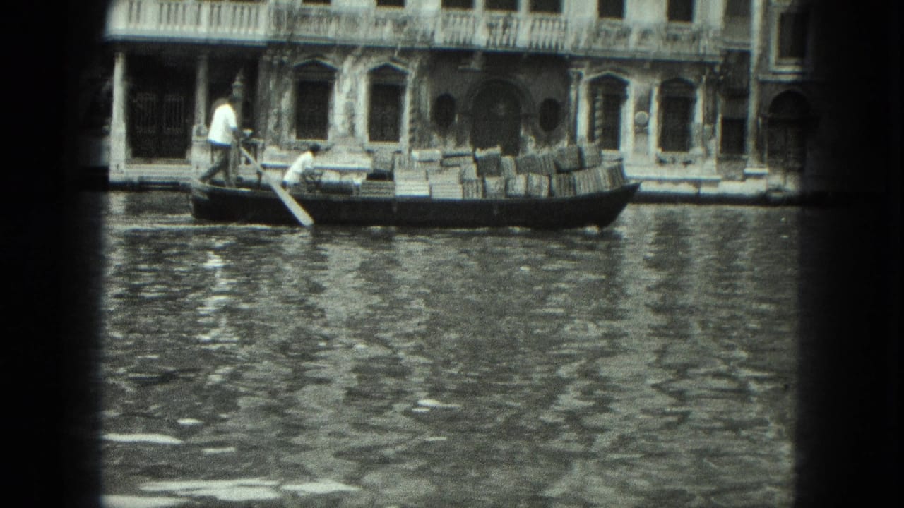 Gondola with passengers and cargo moving along a canal beside ornate buildings.