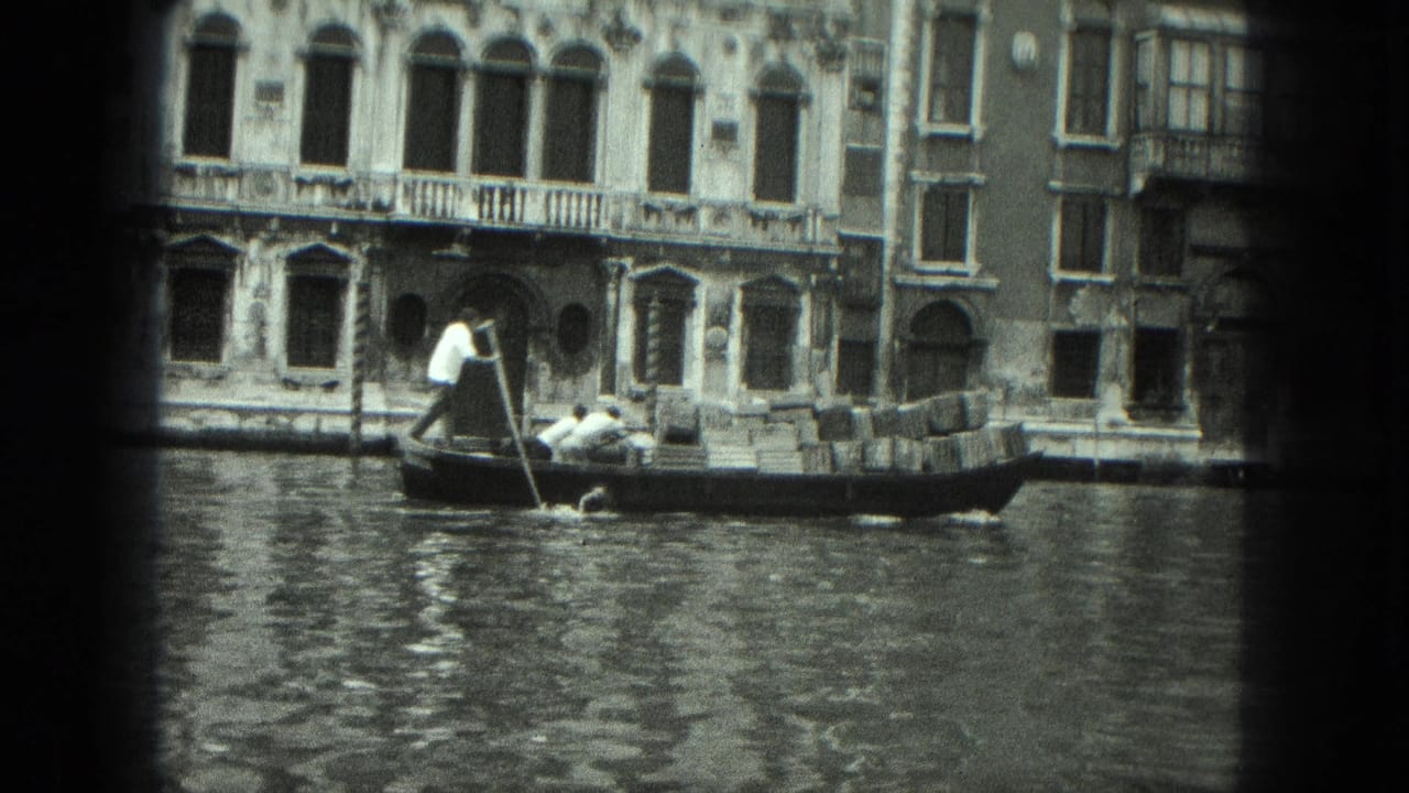 Loaded gondola passing historic canal-side buildings with arched windows.