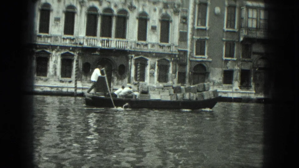 1975 Venice home-movie frame of a gondola carrying passengers and cargo along rippling canal water.