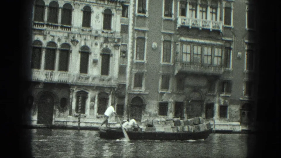 1975 Venice 8mm frame with a low-framed gondola passing multi-story canal buildings and balconies.