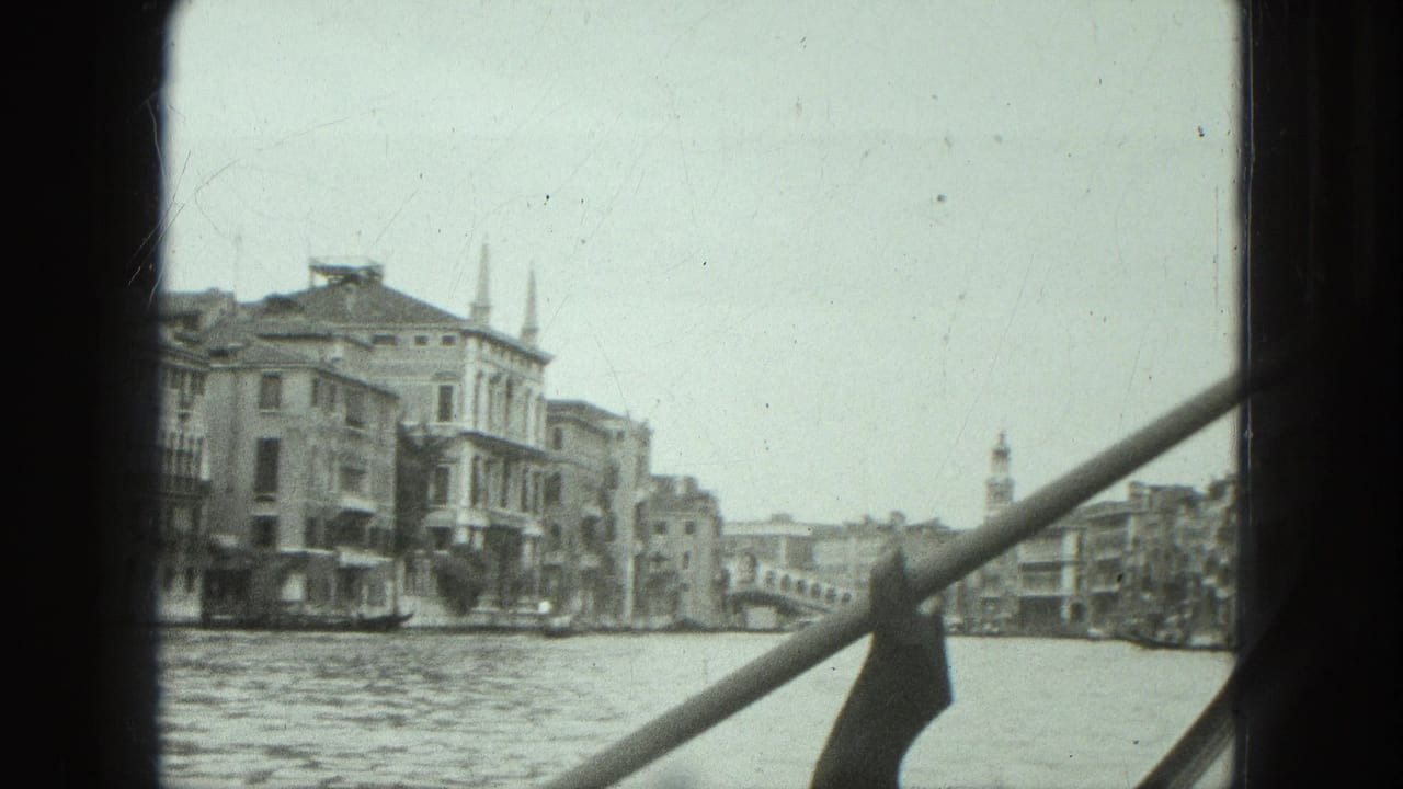 1975 Venice canal view from inside a gondola, showing waterfront buildings, a distant bridge, and the rowing pole crossing the frame.