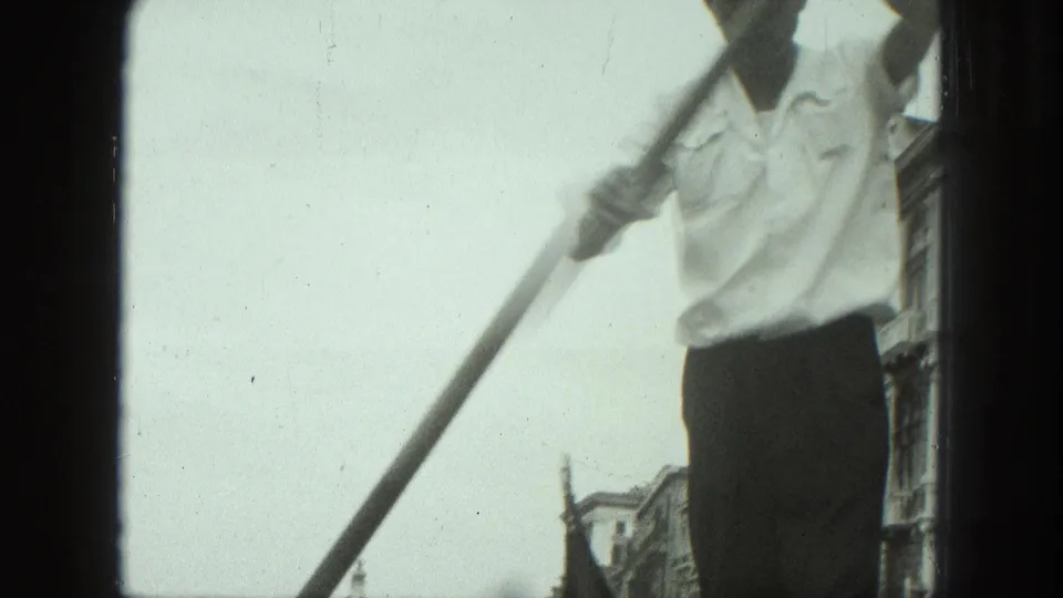 1975 Venice gondola ride with a gondolier partly cropped near the camera, rowing beside canal-side buildings.