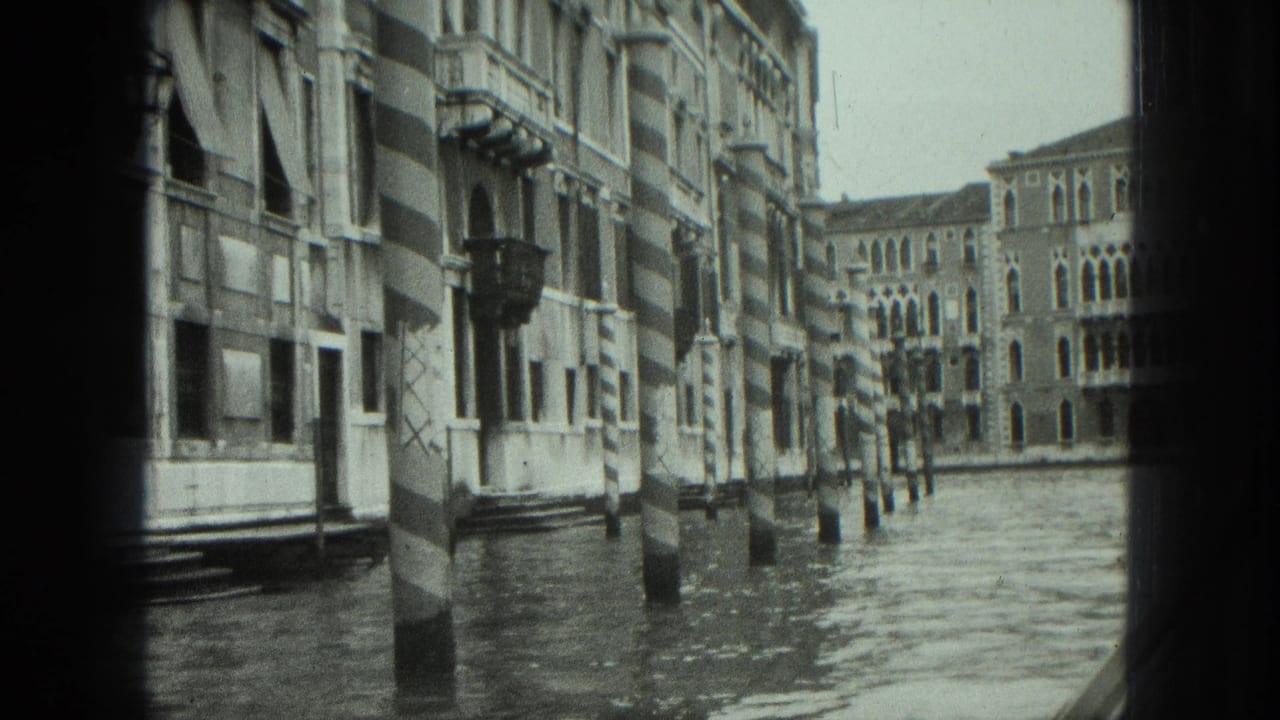 Similar canal view with buildings, striped poles, water, and dark framing from the boat.