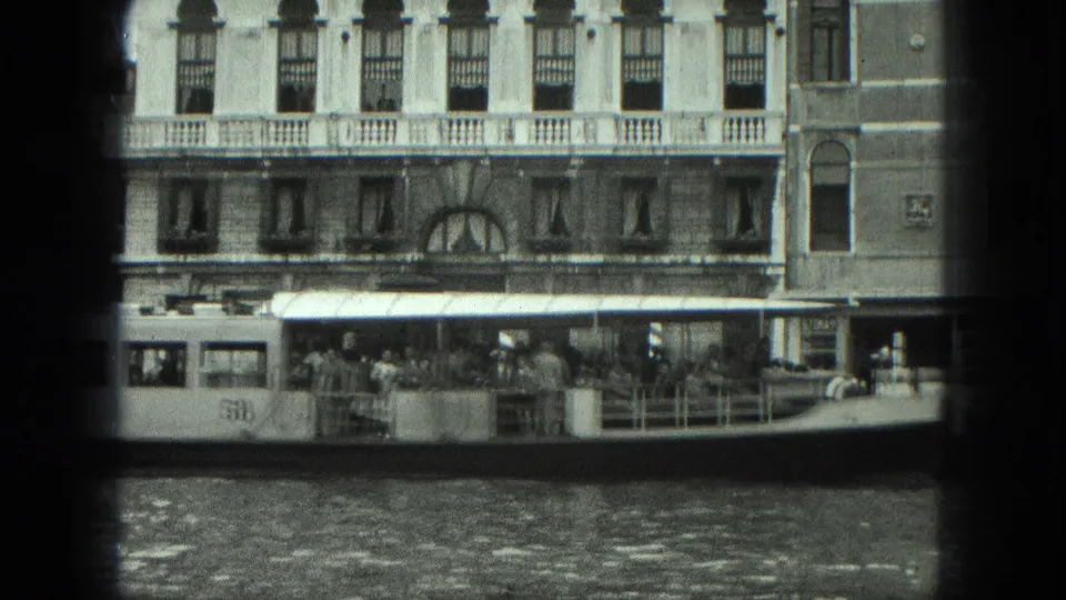 1975 Venice water bus marked 58 carrying passengers along the canal in front of a multi-story waterfront building.