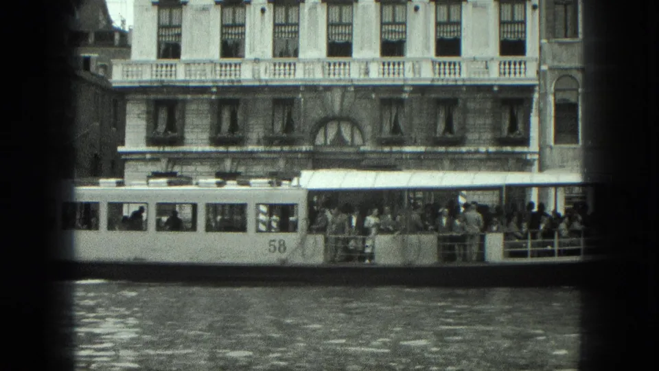 1975 Venice water bus number 58 carries visible passengers beside a waterfront building with awnings and upper-story windows.