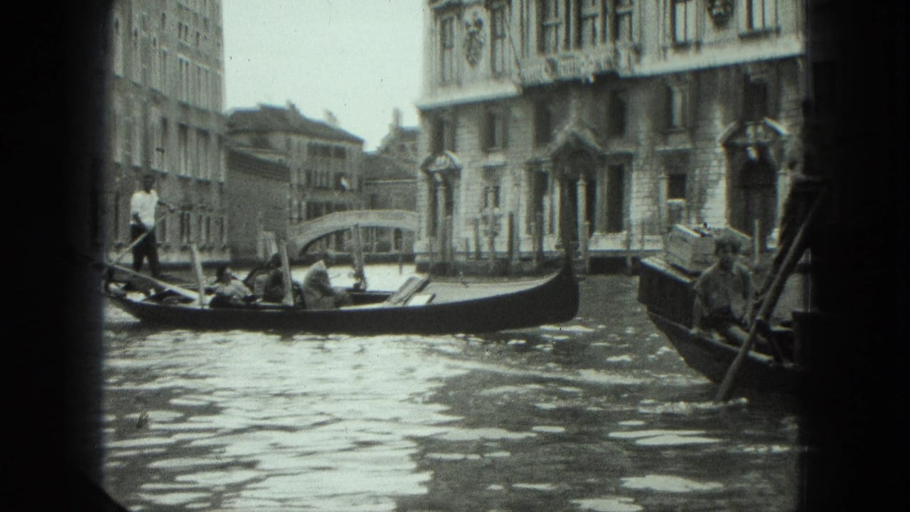 Gondola crosses a canal with a gondolier standing and waterfront buildings behind.