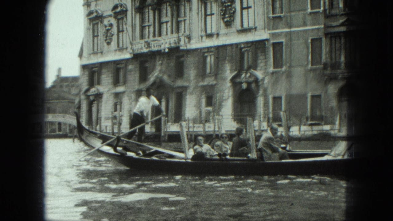 1975 Venice home-movie frame showing a gondolier standing at the stern while tourists sit in a gondola near canal-front architecture.