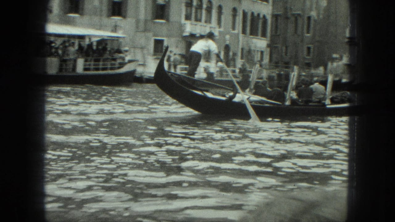 Gondolier rows a gondola with passengers along a Venetian canal.