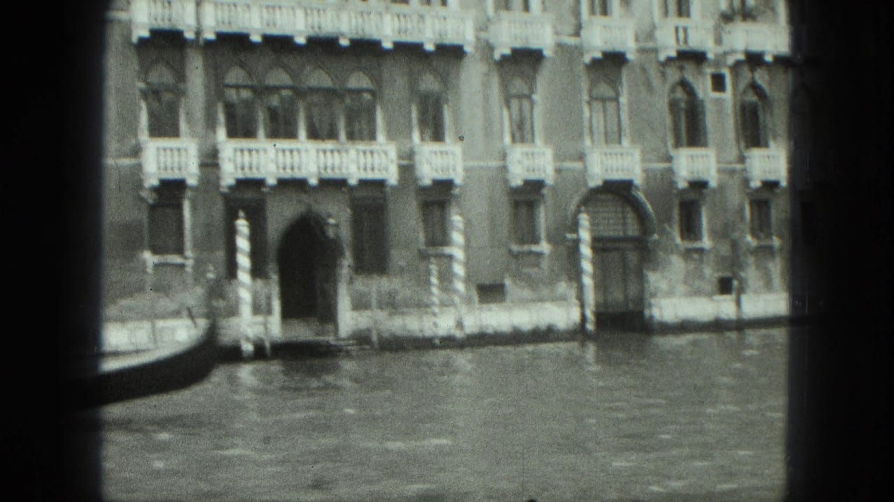 Canal-side building facade with arched entryways and water in front.