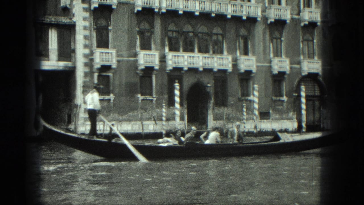 Gondolier standing on a gondola beside a Venetian canal facade.