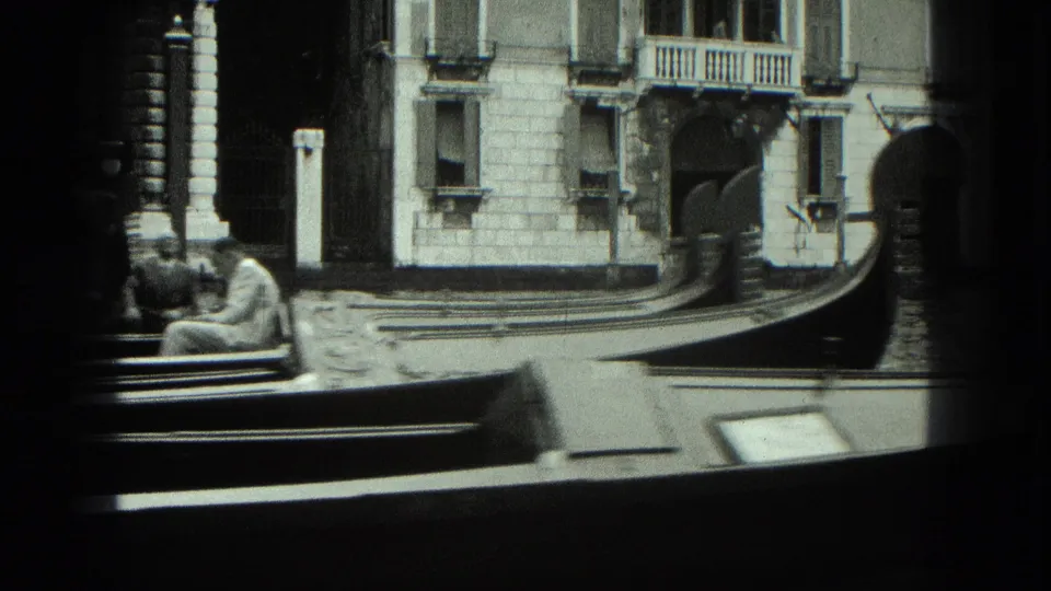 1975 Venice 8mm frame showing a gondola bow in the foreground with ornate canal-side facades behind it.