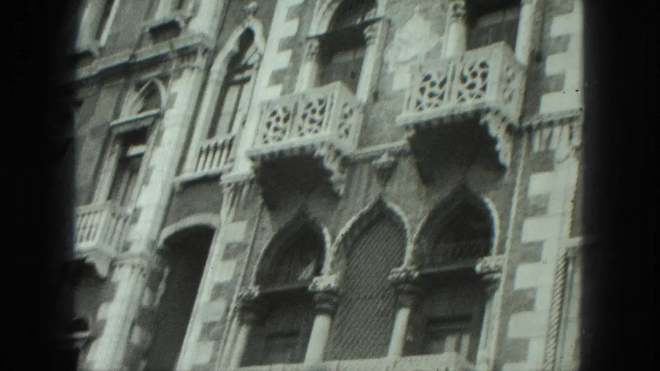 1975 Venice home-movie frame showing an ornate canal-side facade with arched windows, columns, and decorative balconies.