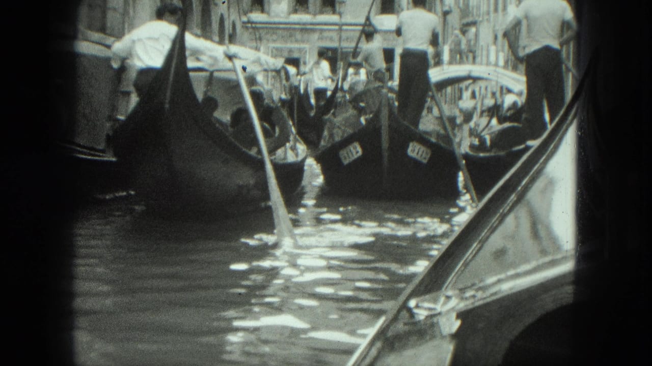 Tour gondolas move through canal traffic beside buildings and a small bridge.