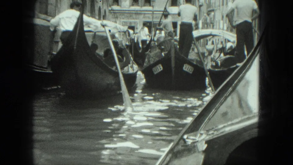 Venice, Italy canal view from a moving gondola with gondoliers rowing nearby tour boats in bright daylight.