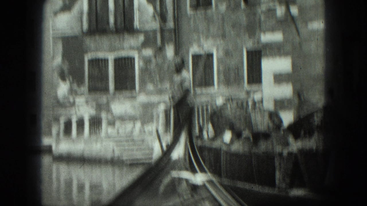 Blurred gondola bow moves past canal-side buildings and shuttered windows.