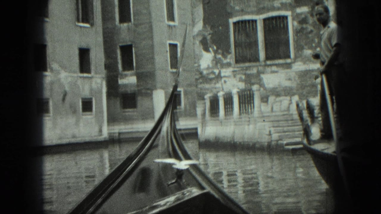 Gondola prow and gondolier passing old canal-side buildings in Venice.