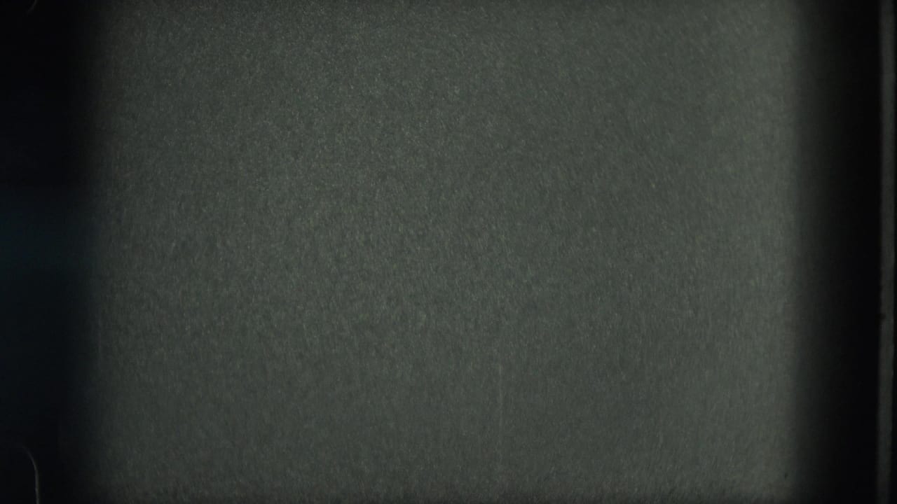 Dark underexposed frame with visible film texture and vertical gate markings.