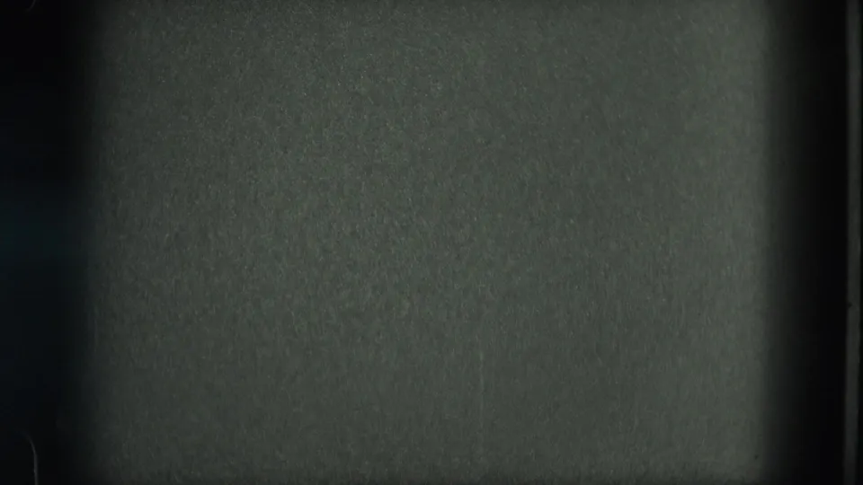 Underexposed 8mm frame from the 1975 Venice footage, with film grain and gate markings but little readable scene content.