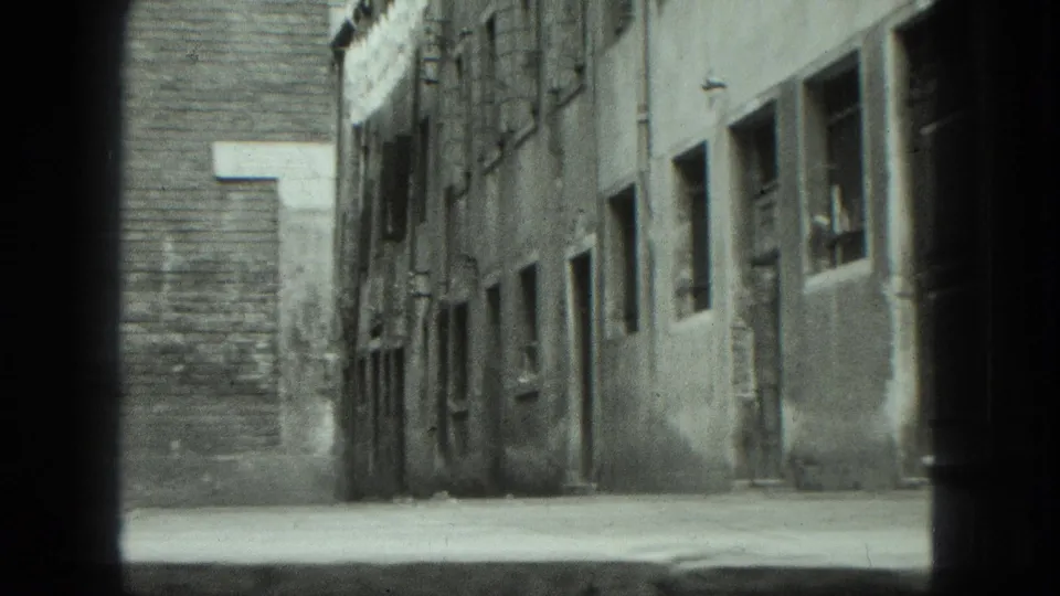 A brief Venice street-side view shows a paved lane, weathered walls, small windows, and no visible pedestrians.