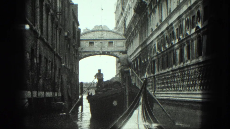 A 1975 black-and-white Venice canal view shows a standing gondolier, a boat, a gondola prow, and the Bridge of Sighs ahead.
