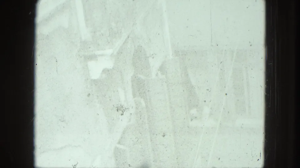 Overexposed 8mm frame from the Venice clip, with faint facade shapes and visible surface marks on the scanned film.