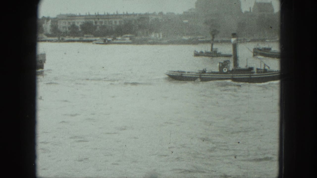 Harbor water with a small dark funnel boat and distant shoreline seen through film gate edges.