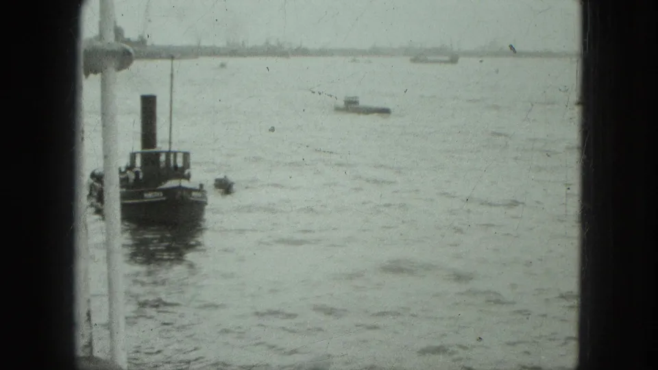 Venice harbor water fills the frame as a dark funnel boat sits beside a white window frame and small vessels appear on the horizon.