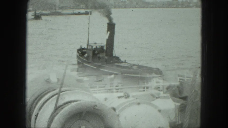 1975 Venice harbor footage showing a smoking tugboat on the water beyond rounded ship deck machinery and railings.