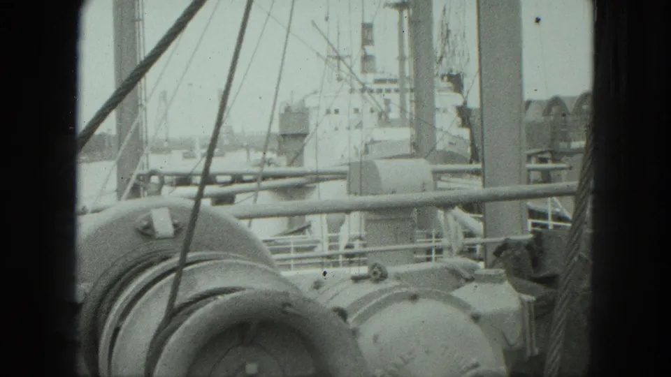 1975 Venice ship deck detail with winch-like machinery, slanting rigging, railings, and a docked vessel in the background.