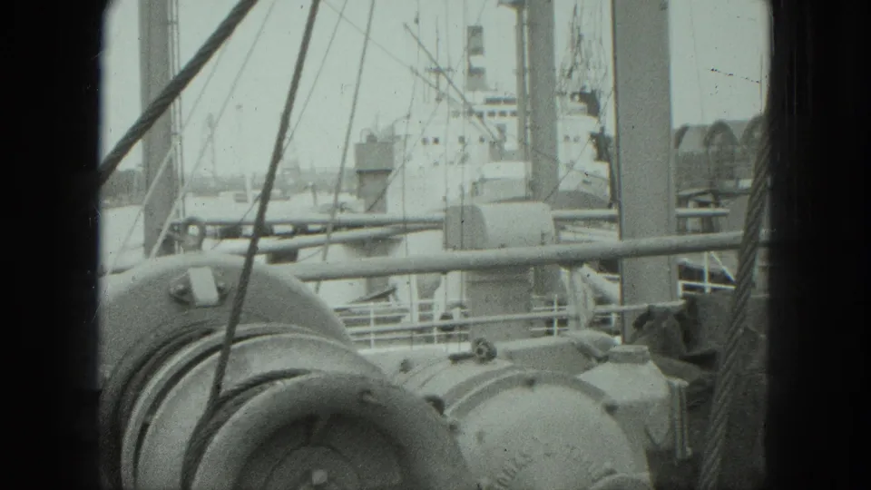 1975 Venice harbor deck view showing rounded machinery, rigging lines, railings, and distant vessel details in soft 8mm texture.