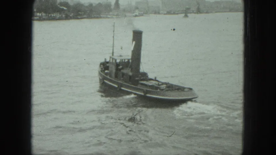 1975 Venice harbor view of a small tugboat with a tall smokestack leaving a wake on calm water.