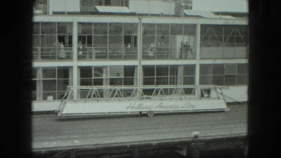 A 1975 Venice passenger-port view frames the terminal facade, gangway lettering, pier, and figures seen through windows.