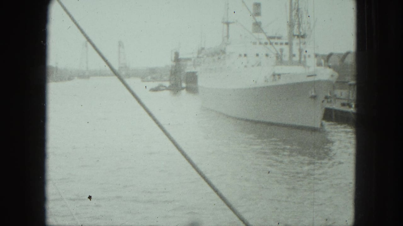 1975 Venice harbor view with a large white ship at dock, rigging lines across the frame, and soft 8mm film texture.
