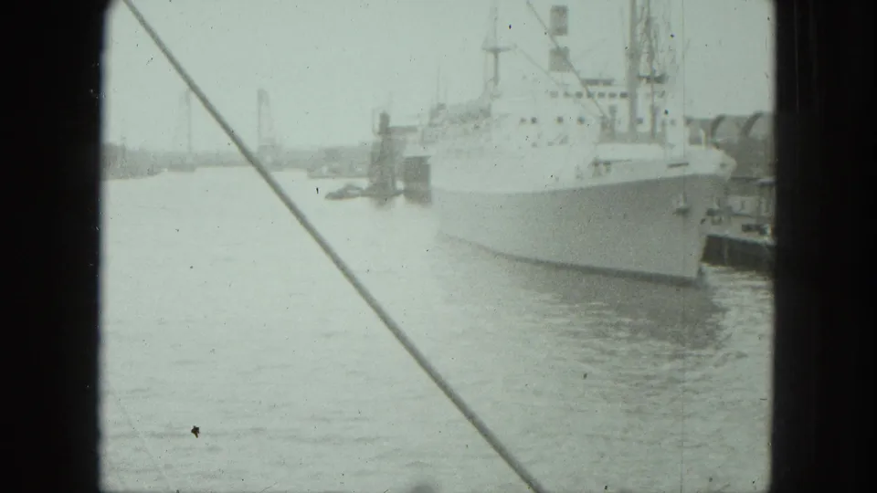 1975 Venice harbor view with a large white ship at dock, rigging lines across the frame, and soft 8mm film texture.