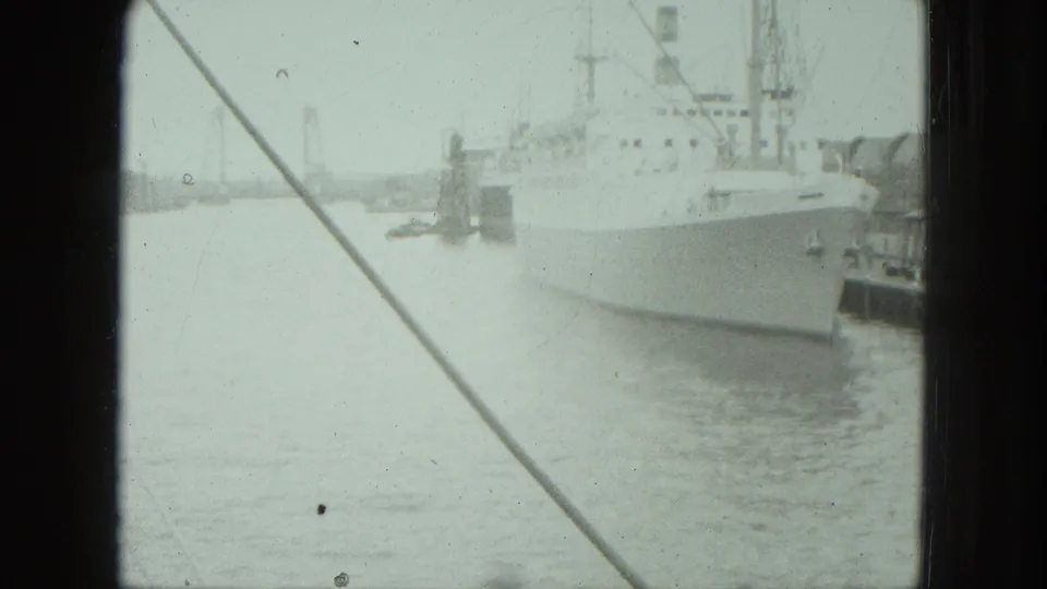 A white vessel remains docked in the Venice harbor while diagonal rigging and dark film borders frame the soft 8mm view.