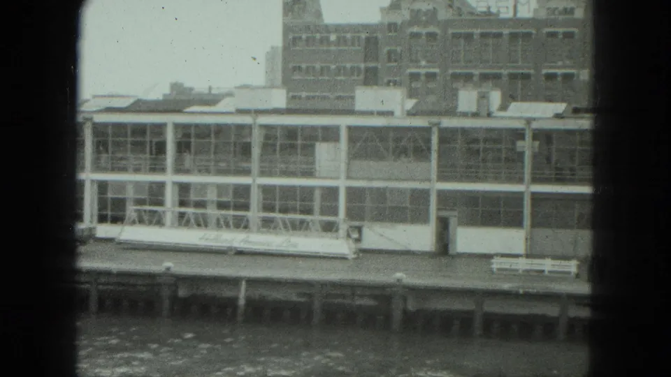 1975 Venice waterfront view of a white glass-fronted pier structure across choppy water, seen through dark framing.