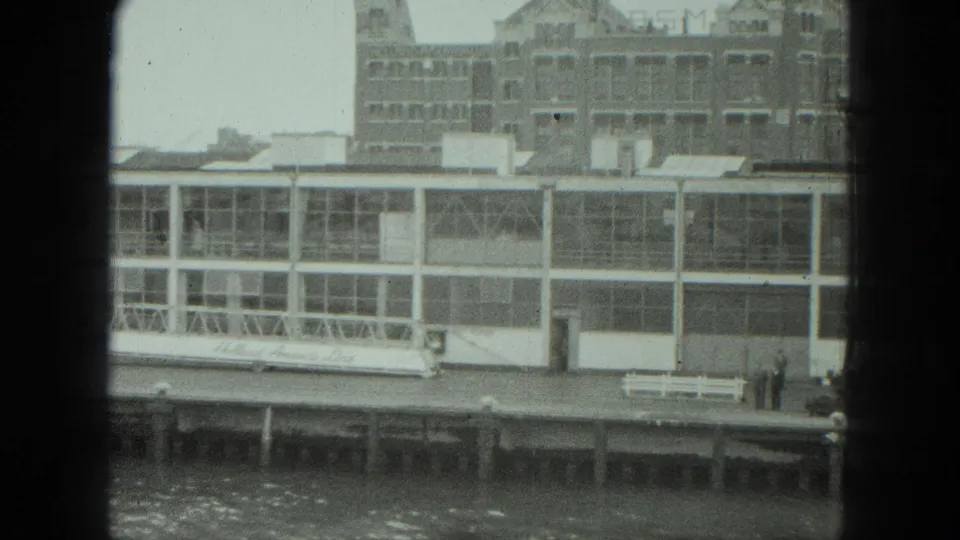 1975 Venice dock view with a long white waterfront structure, bench, and two distant people standing near the pier.