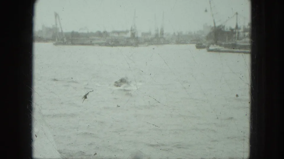 1975 Venice waterfront view with choppy water, small craft, cranes, and industrial shoreline seen through dark framing.