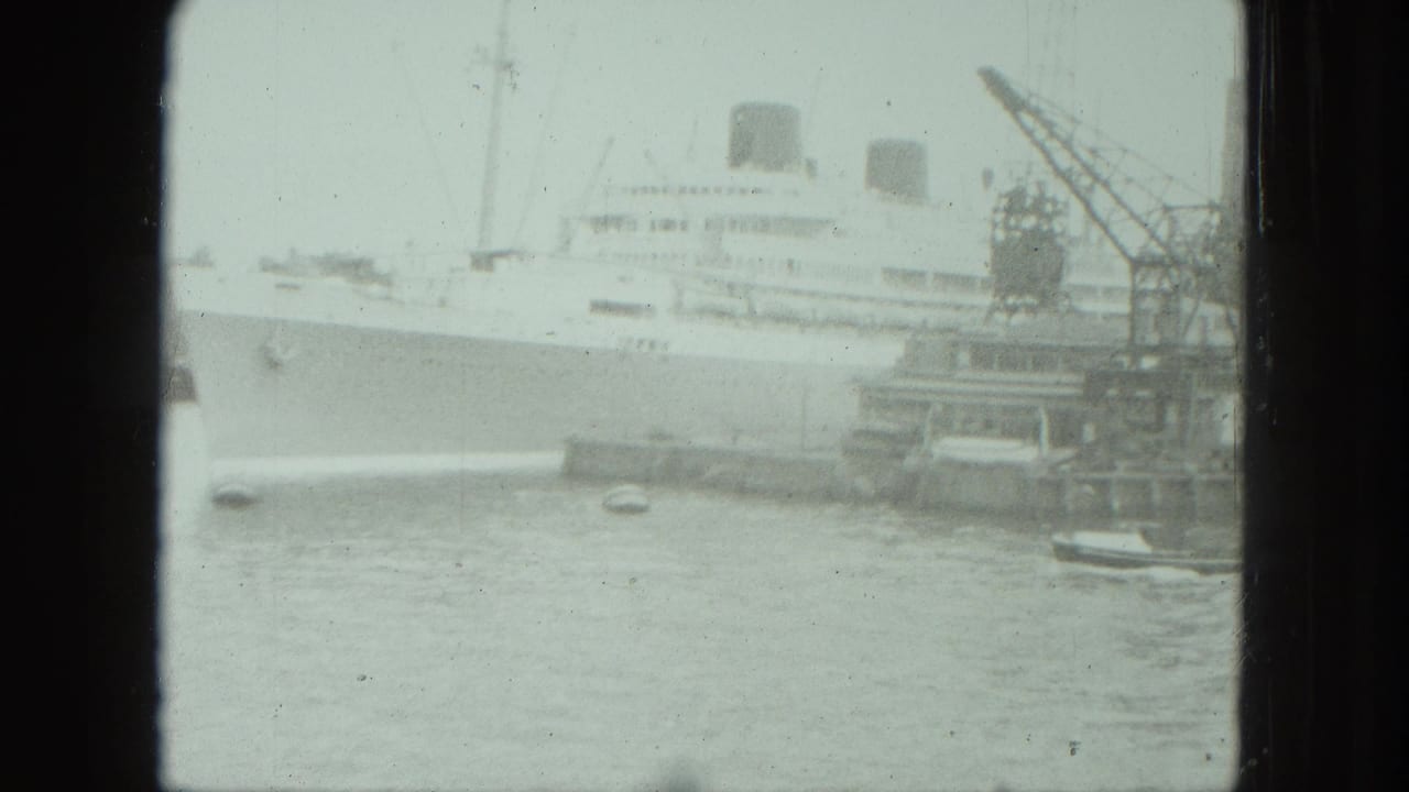 1975 Venice harbor view of a large white passenger ship near dock cranes, with small boats in the foreground water.