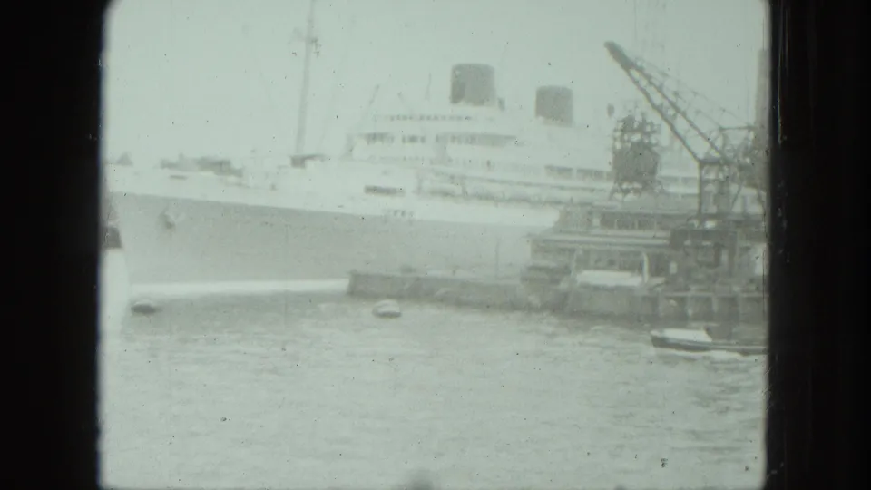 1975 Venice harbor view of a large white passenger ship near dock cranes, with small boats in the foreground water.