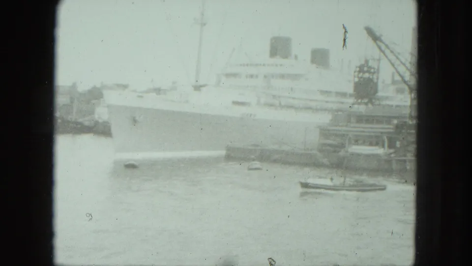 1975 Venice waterfront frame showing a large passenger ship, crane structures, and small craft emphasizing the ship's scale.