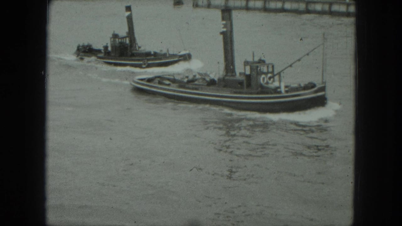 1975 8mm Venice frame showing two tugboats traveling on a broad waterway near the waterfront.