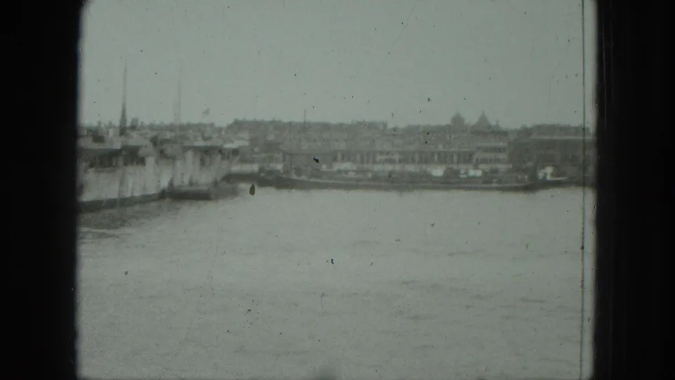 1975 8mm Venice view of a large vessel along the left edge, open water, and distant waterfront buildings.