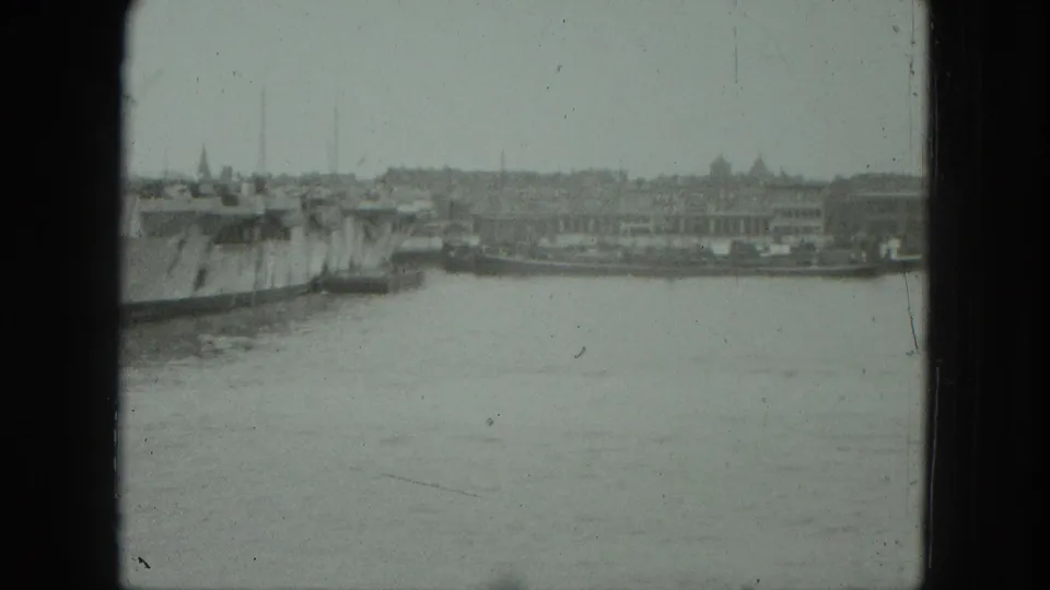 1975 8mm Venice frame showing a wide waterway, a large vessel, and a distant urban shoreline.