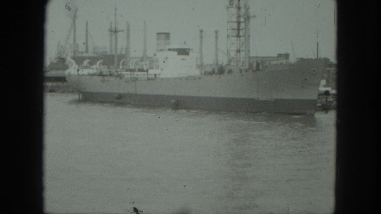 Moored ship beside harbor structures, framed by dark film edges.